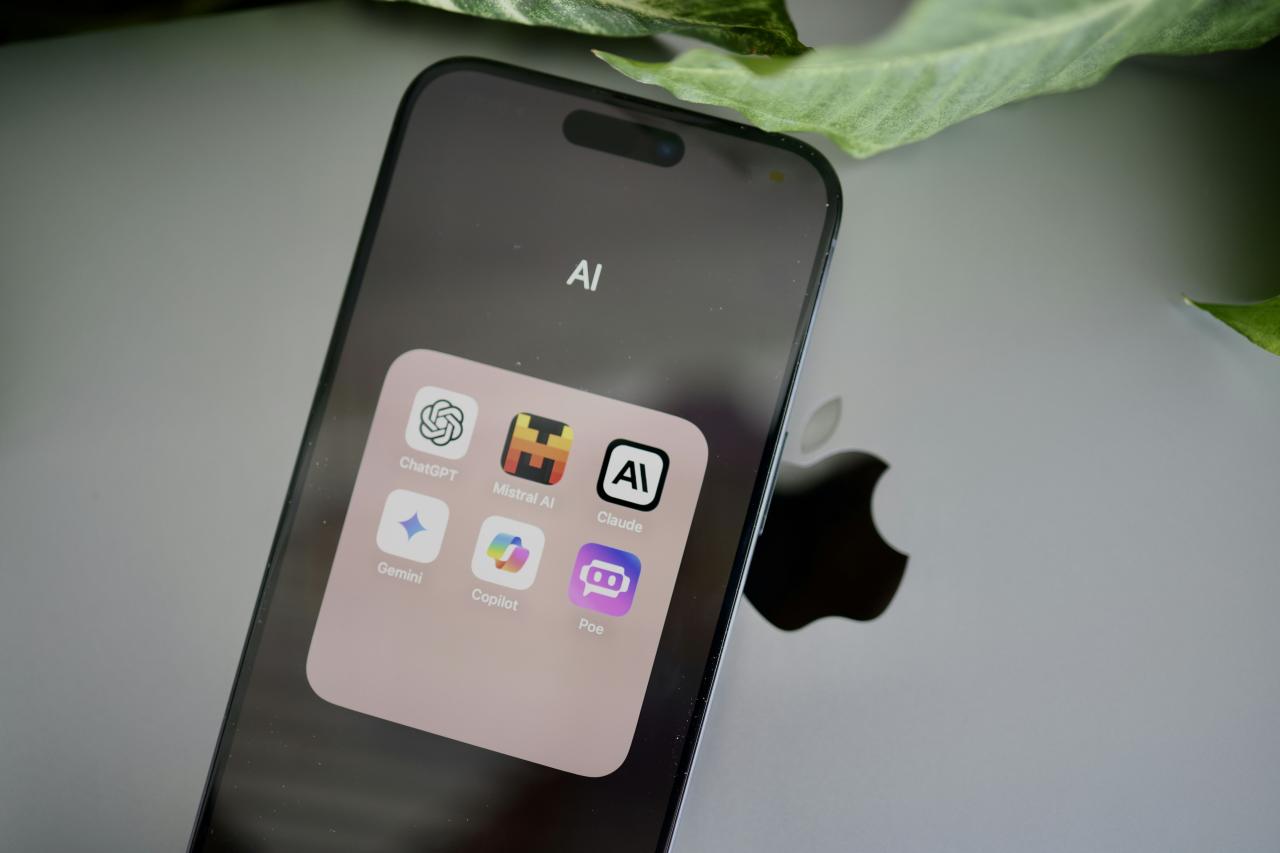 iPhone yang duduk di atas meja di sebelah daun