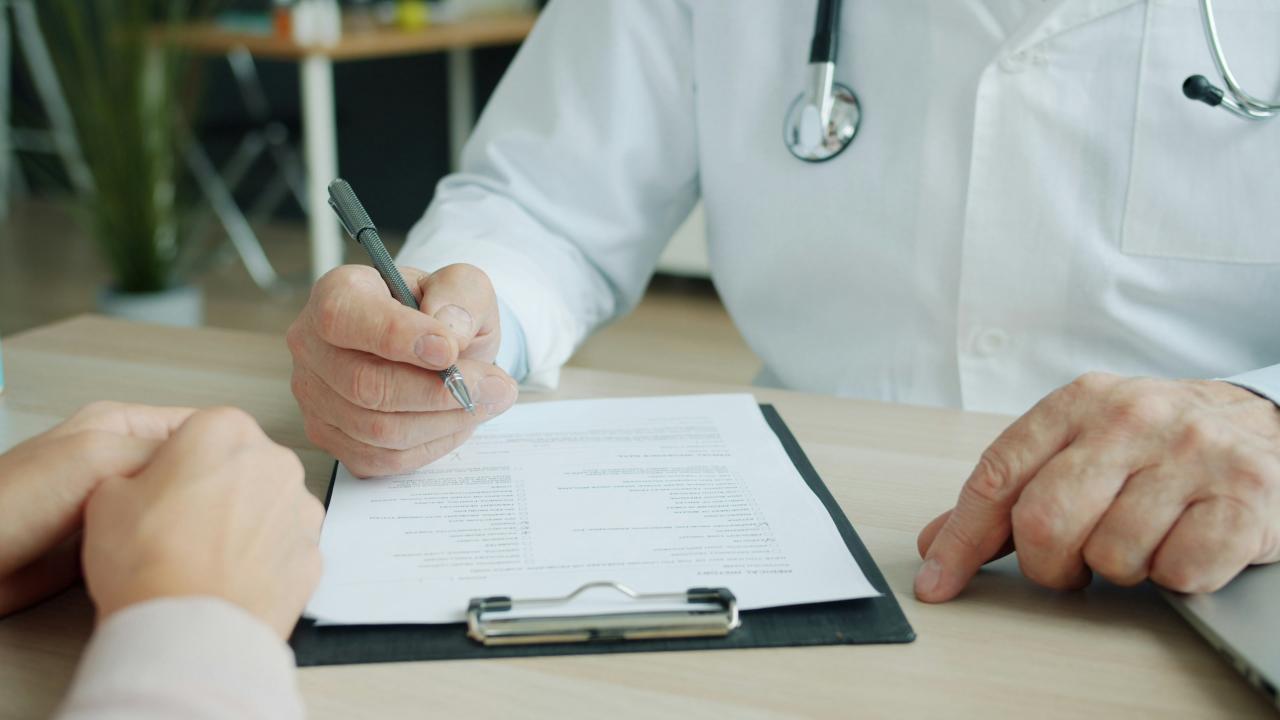 Dokter menulis pada bagan pasien